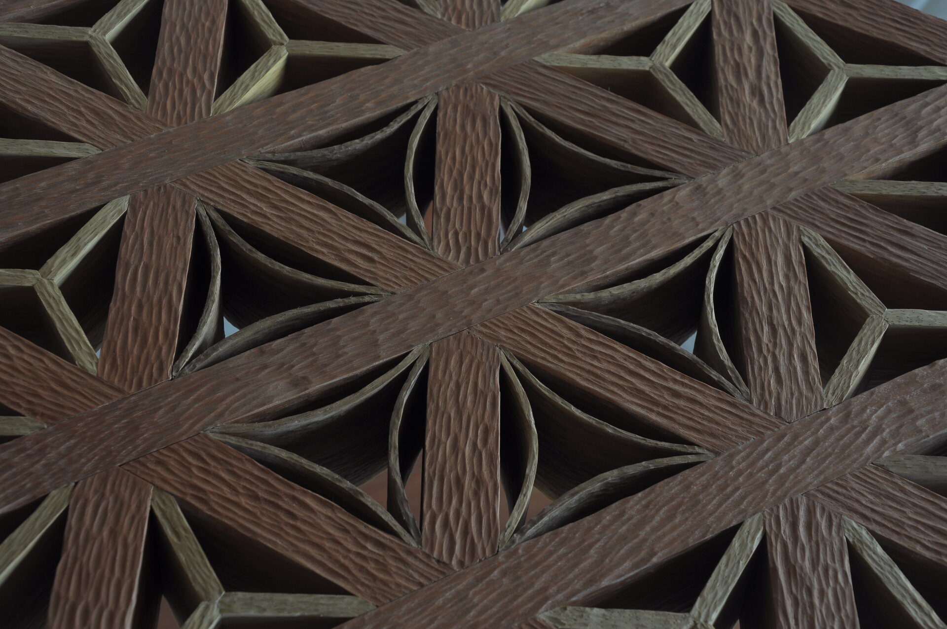 Close-up of a hand-carved geometric wooden lattice with a repeating floral-star pattern.